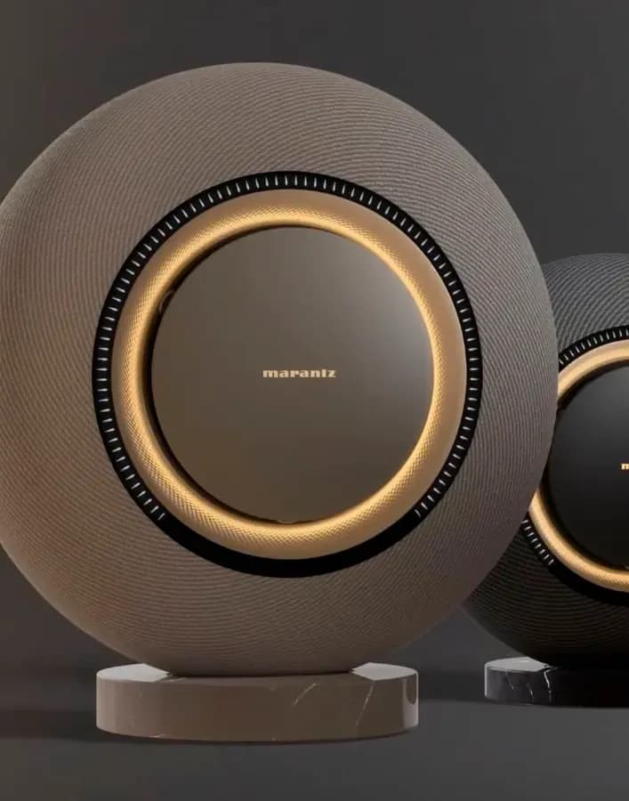 Circular Marantz speaker with golden accents and a textured exterior on a marble base.