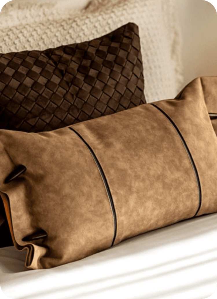 Decorative cushions in earthy tones on a natural knit – Soft textiles combining suede and woven textures, conveying warmth and comfort.