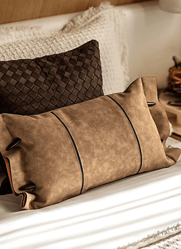 Set of decorative cushions in brown and tan leather textures on a bed, soft neutral tones and cozy lighting.