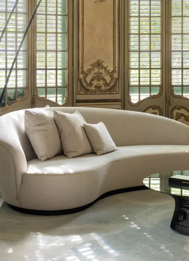 Curved beige sofa with cushions in a historic interior · LUV Lifestyle FF&E